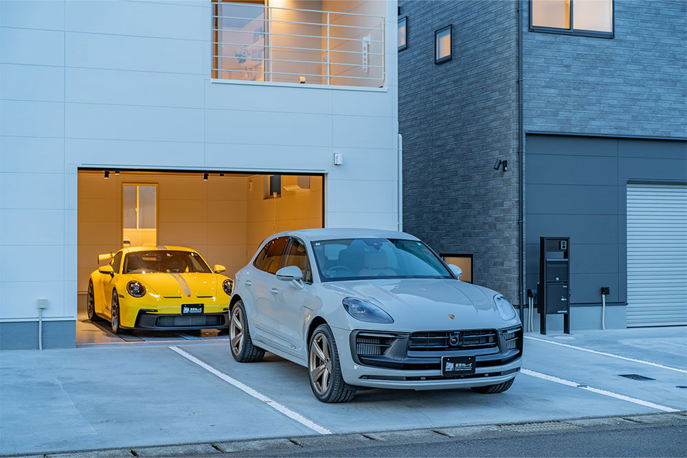 B棟ガレージに駐車したポルシェ911 GT3と屋外に駐車したマカンGTS